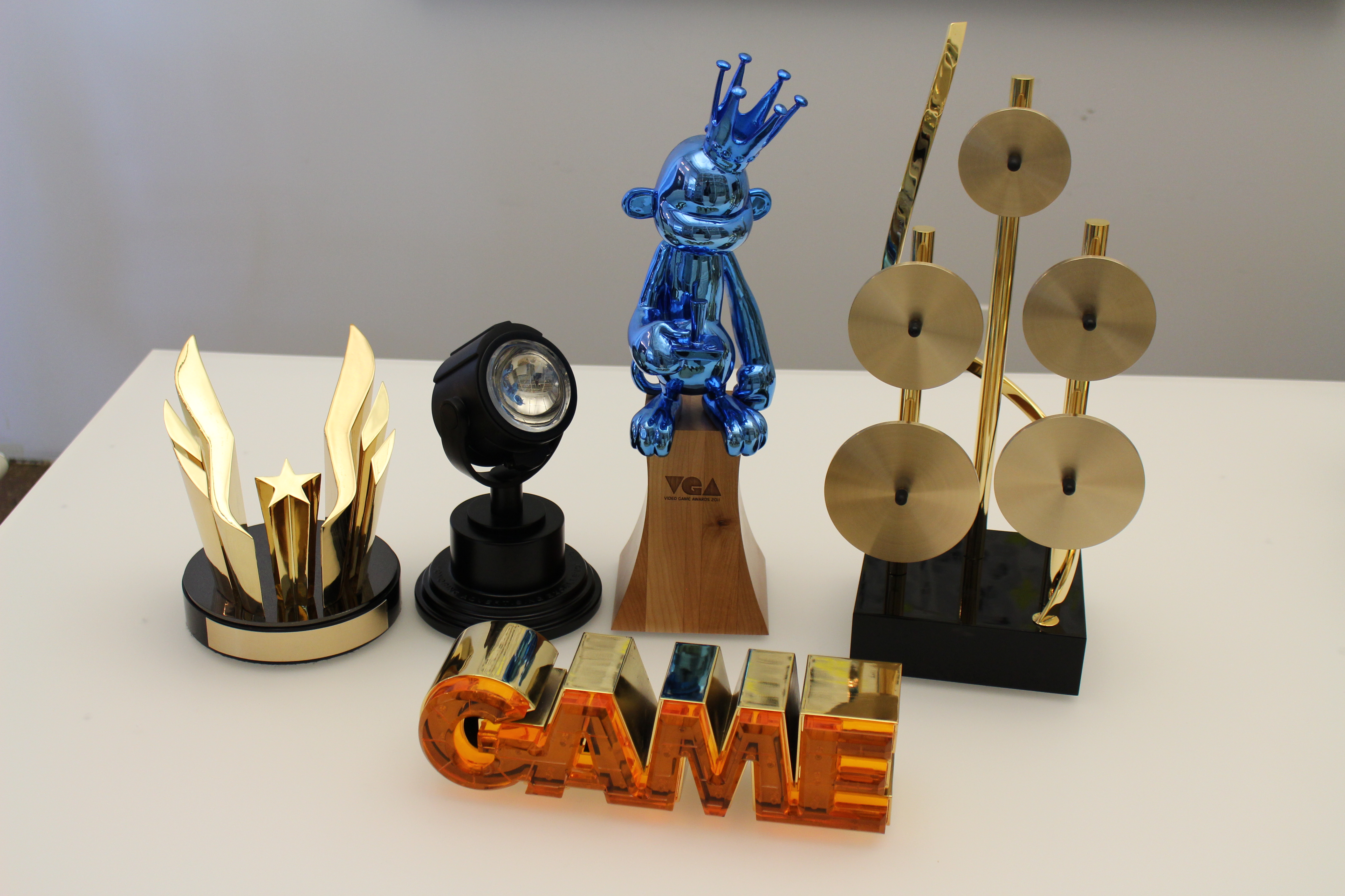 5 custom trophies on a white table. Left to right: USATF Wing, Clio Key Art, VGA, SOCAN; Front: Hall of Game