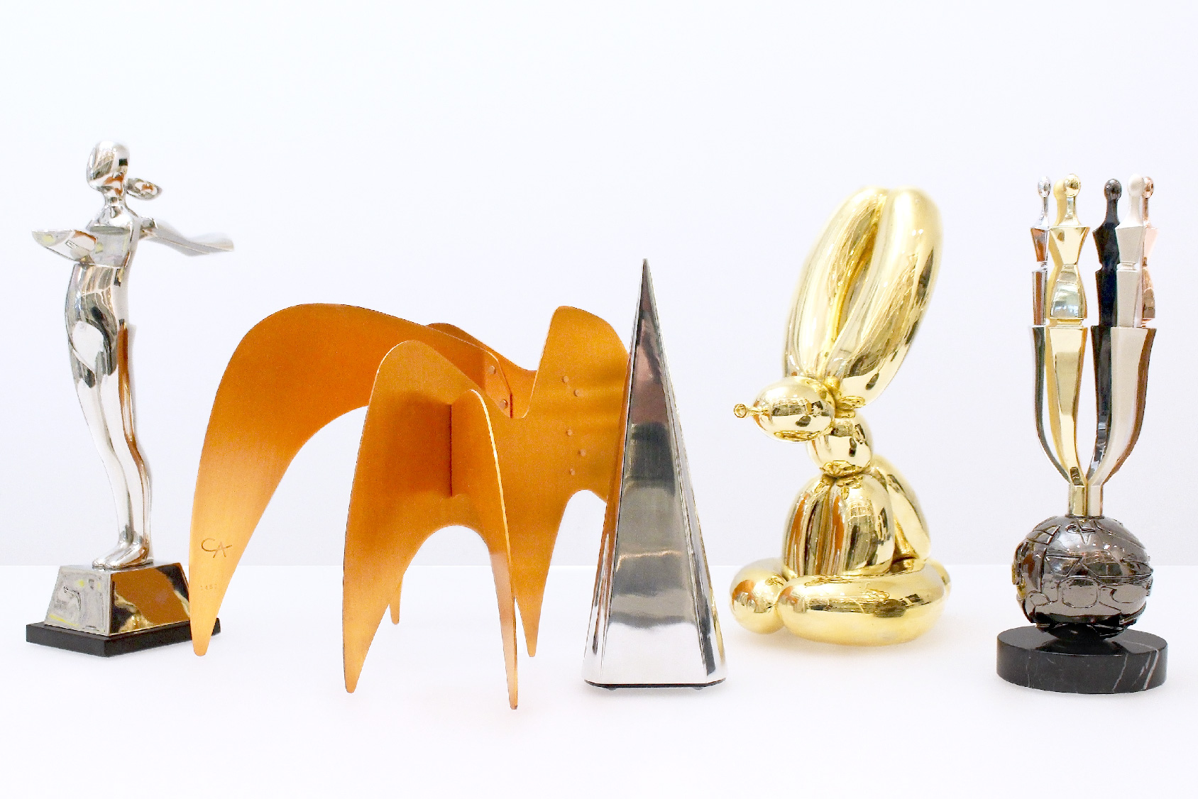 Five custom metal trophies grouped on white table in Society Awards office