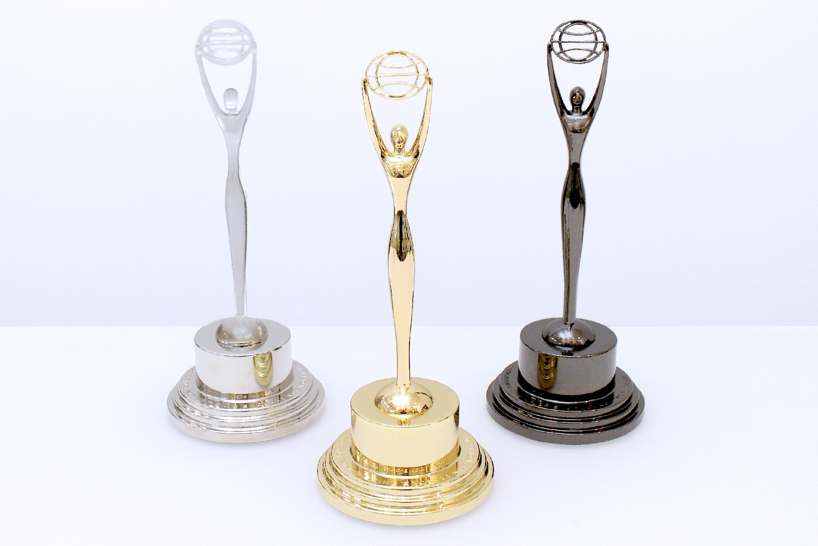Three Clio trophies in crystal, gold and black displayed on a white table at Society Awards NYC headquarters