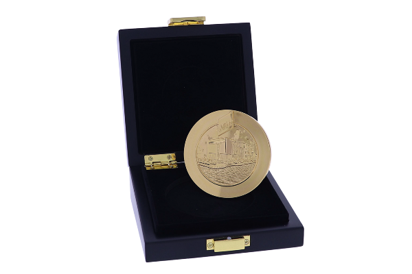 Gold medal with building depiction in a black box