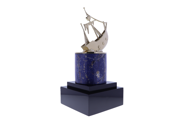 A gold ship sits atop a blue marble cylinder, all atop a tiered black base