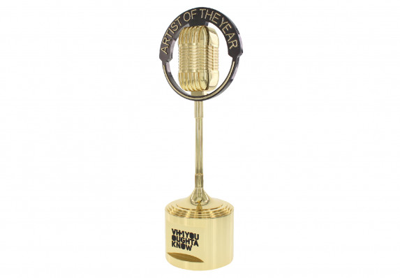 Gold metal microphone trophy presented to artist of the year at music awards show.