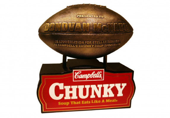 Cast resin metal plated football with raised lettering on wood base with shiny brass screen printed plate