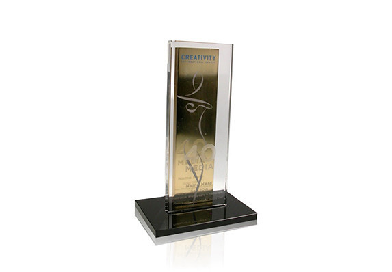 Gold plated metal upright plaque with clear crystal plaque mounted on black base.