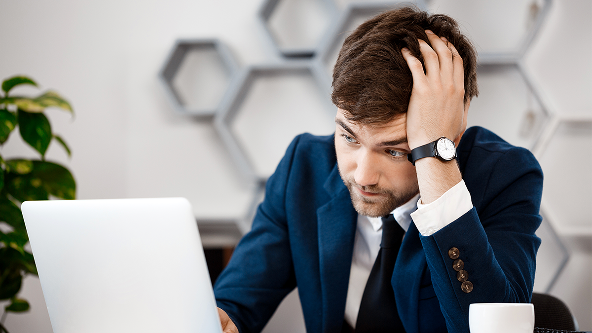 Frustrated Business man holding his head and looking at his laptop