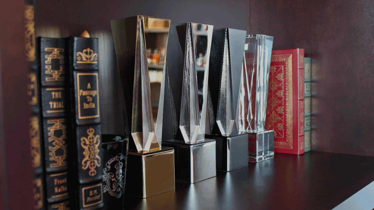 Society Awards Gatsby collection on a bookshelf. The Gatsby Gold, Silver, and Crystal trophies