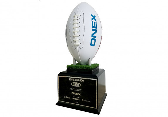 Football personalized with logo and mounted on large base, given for the close of an acquisition deal.
