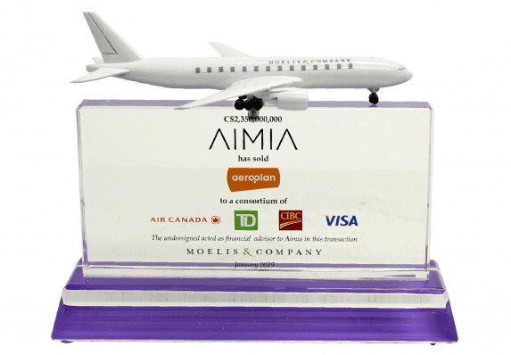 This financial tombstone plaque was crafted to commemorate the sale of a company to a consortium of brands. A model airplane atop the central plaque ads a playful element.