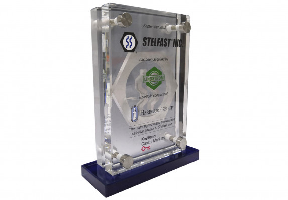 This piece, celebrating the successful close of a brand acquisition, incorporates two panels held together with metal attachments and mounted on a blue base.