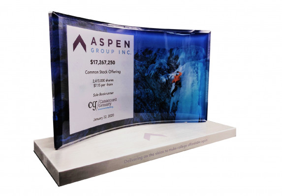 A luxury deal toy with color printed image and tombstone copy on a curved crystal mounted on an aluminum base for a common stock offering.