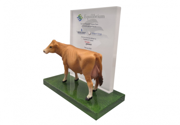 A custom financial tombstone with a model cow mounted on a black crystal base.