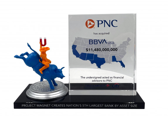 A custom financial tombstone with models and a clear tombstone plaque with acquisition details.