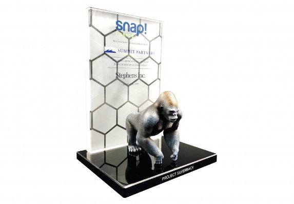 A luxury deal toy with a model ape mounted on a black base. The details of the financial investment are displayed on a large, reverse-printed crystal plaque.