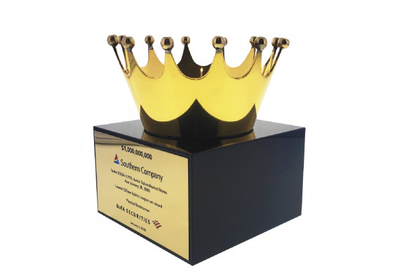 A shiny gold plated crown is mounted atop a modern black base in this elegant financial tombstone for a subordinated debt transaction.