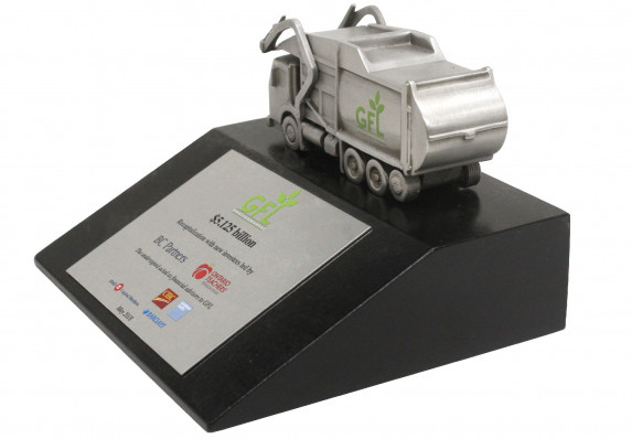 This unique deal toy features a cast metal garbage truck mounted on a black base with a color printed financial tombstone plate.