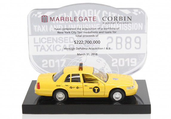 A custom tombstone crafted for the successful close of a deal to acquire a portfolio of taxi medallions. The design incorporates a model taxi and a transaction plaque with a mock medallion.