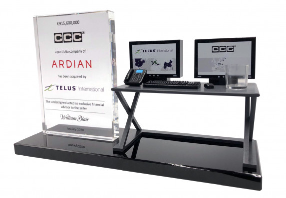 A crystal financial tombstone with deal details is presented on a large crystal base alongside a highly-detailed model desk with computers. This unique deal toy was presented for a telecommunications company acquisition.